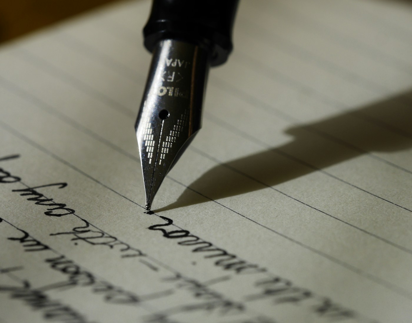 Close-up of a fountain pen resting on handwritten notes